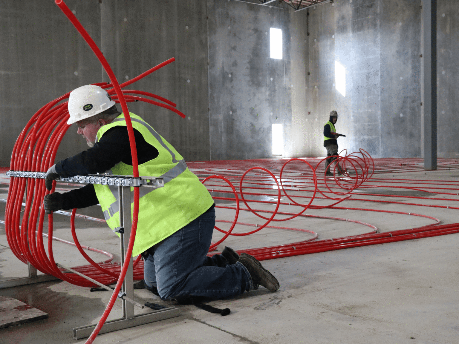 Construction worker manipulating red pipes