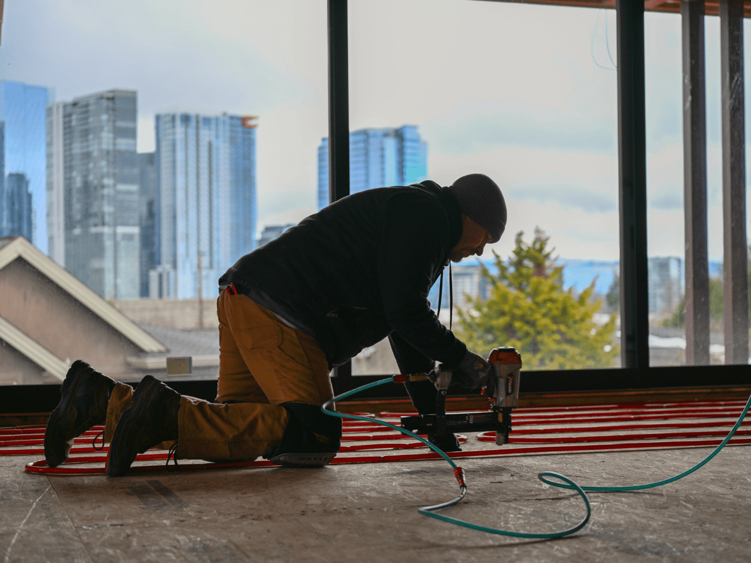 Janes worker kneeling and installing tubing with downtown Bellevue in the background