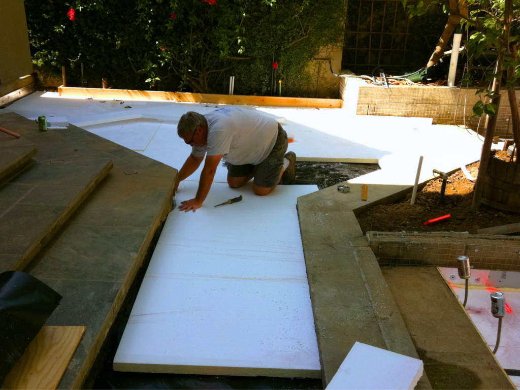 Laying foam over a moisture barrier and man cutting it to size