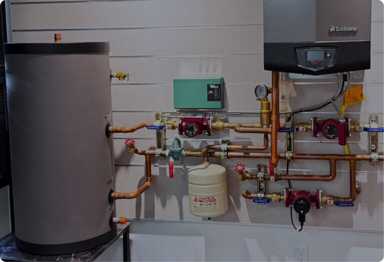 Modern boiler setup on a display wall, showing a large water tank, a boiler, copper pipes, pumps, and various controls.