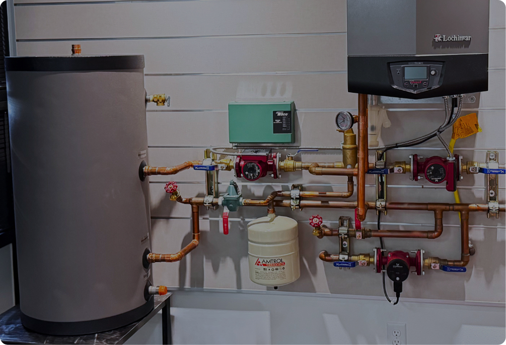 Modern boiler setup on a display wall, showing a large water tank, a boiler, copper pipes, pumps, and various controls.