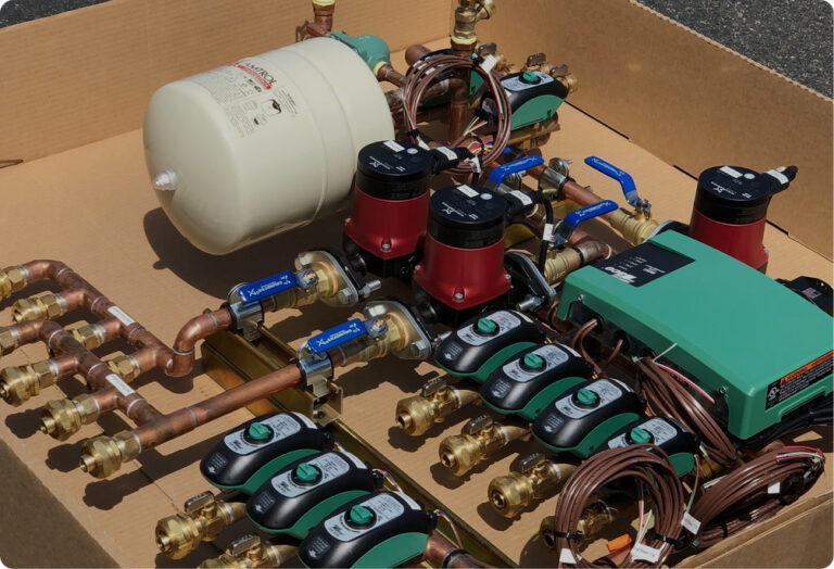 New radiant heating system components: copper manifolds, multiple red circulating pumps, green electronic controls, and a white expansion tank.
