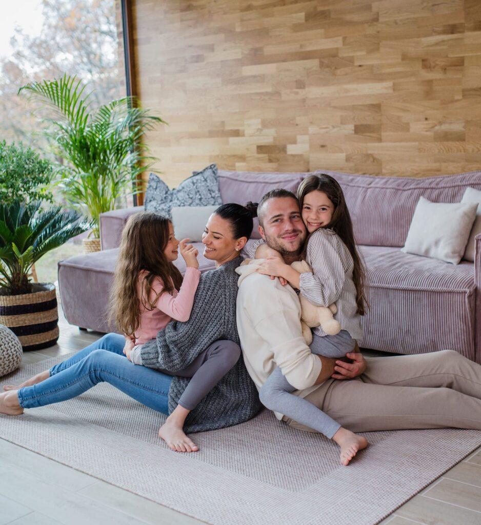 family sitting on floor together barefoot in front of large window