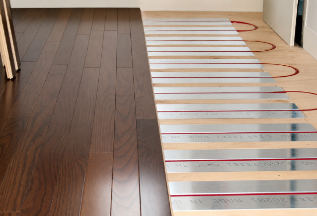Aluminum panels with red tubing under laminate wood floor being installed