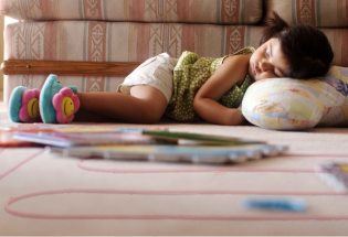 Toddler girl sleeping on the floor surrounded by toys