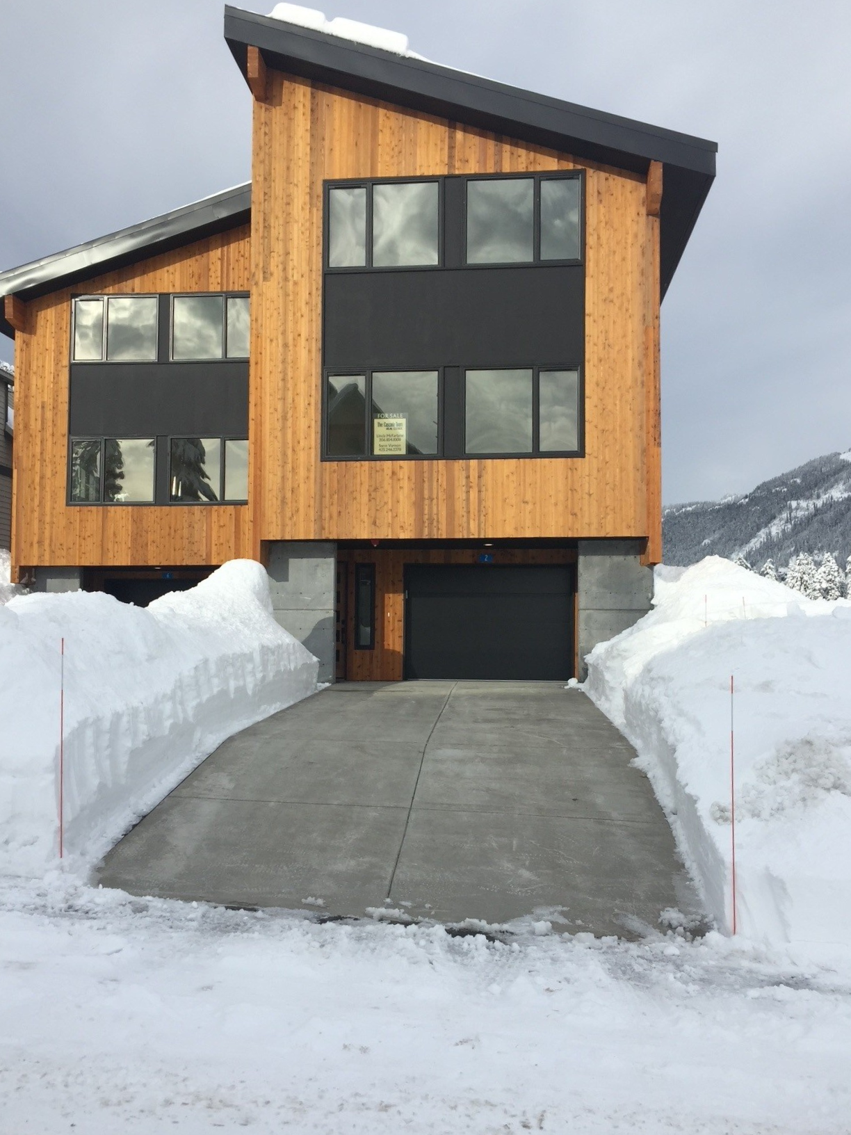 Snoqualmie pass home with snow piled high on both sides of a clear driveway using a snowmelt system