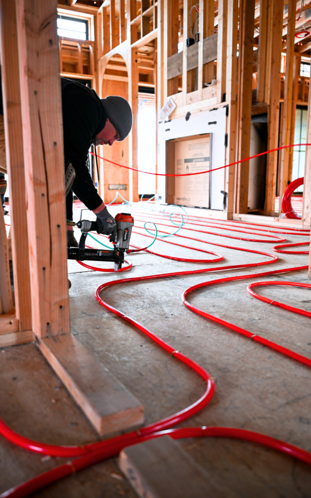 Installing pex tubing over plywood, staple to floor and also showing how to install through doorway before gypsum is added