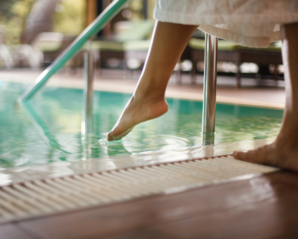 Person in robe checking the pool water temperature with foot. Pool heater repair
