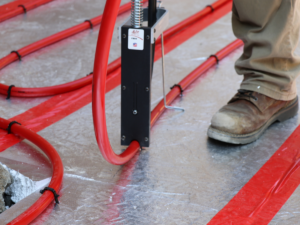 Installer using a FOam Staple gun to attach PEX tubing to Foam that will eventually live inside a concrete slab.