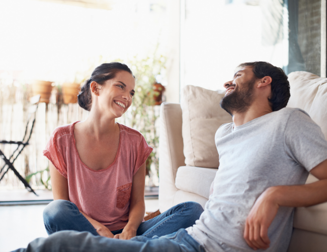 Happy couple sitting on a floor that is heated hydronically. Financing available for boiler replacement